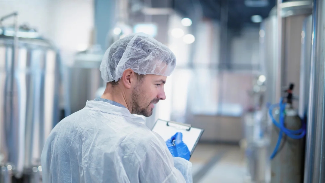 Un homme en lab coat tient un clipboard, symbolisant le processus de copacking dans un environnement de laboratoire.