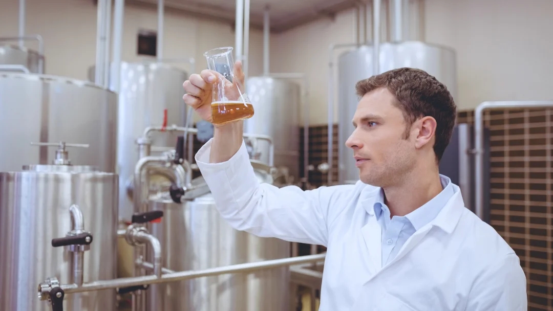 Un homme en lab coat tenant un verre de bière, symbolisant la qualité.