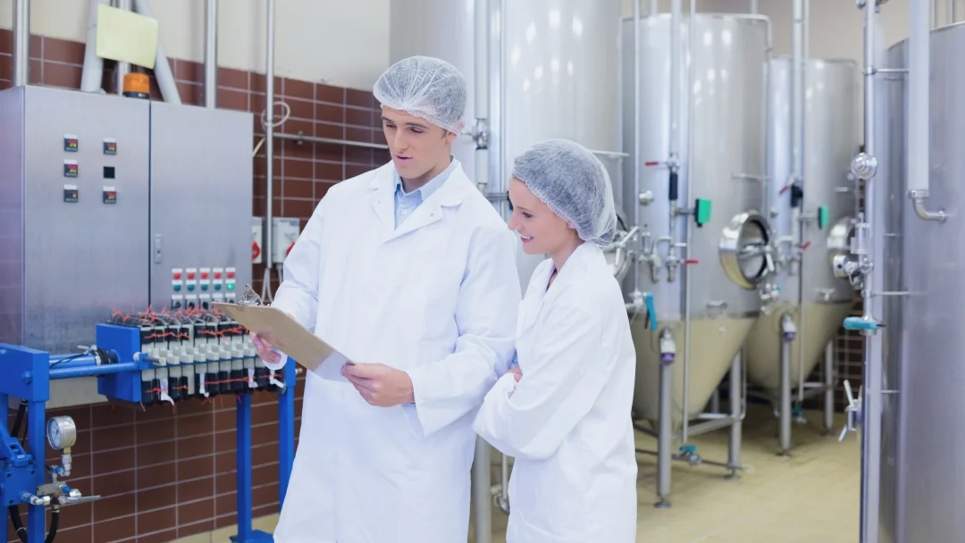 Deux personnes en blouses blanches se tiennent devant un grand réfrigérateur industriel.